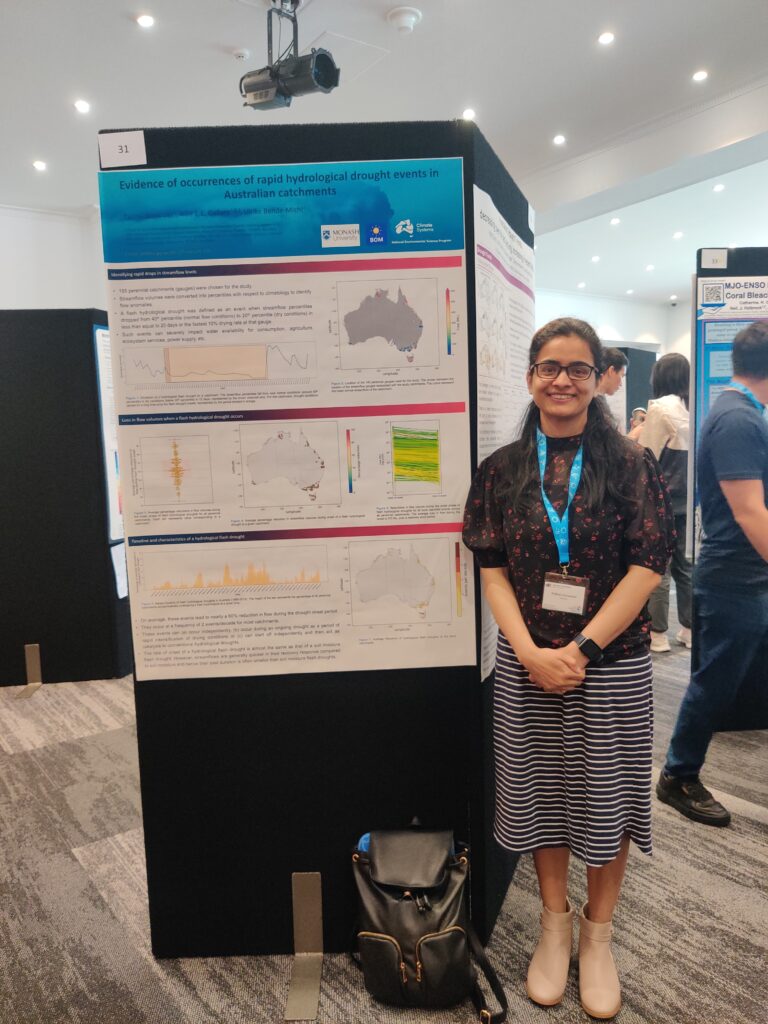 Pallavi standing next to her poster at a conference